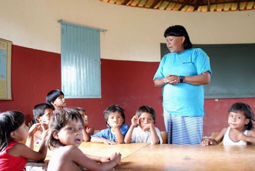 Crianças indígenas em uma sala de aula, com um professor indígena