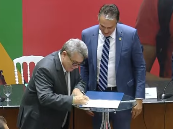 O reitor Eustáquio de Castro assinando o termo de posse ao lado do ministro da Educação.