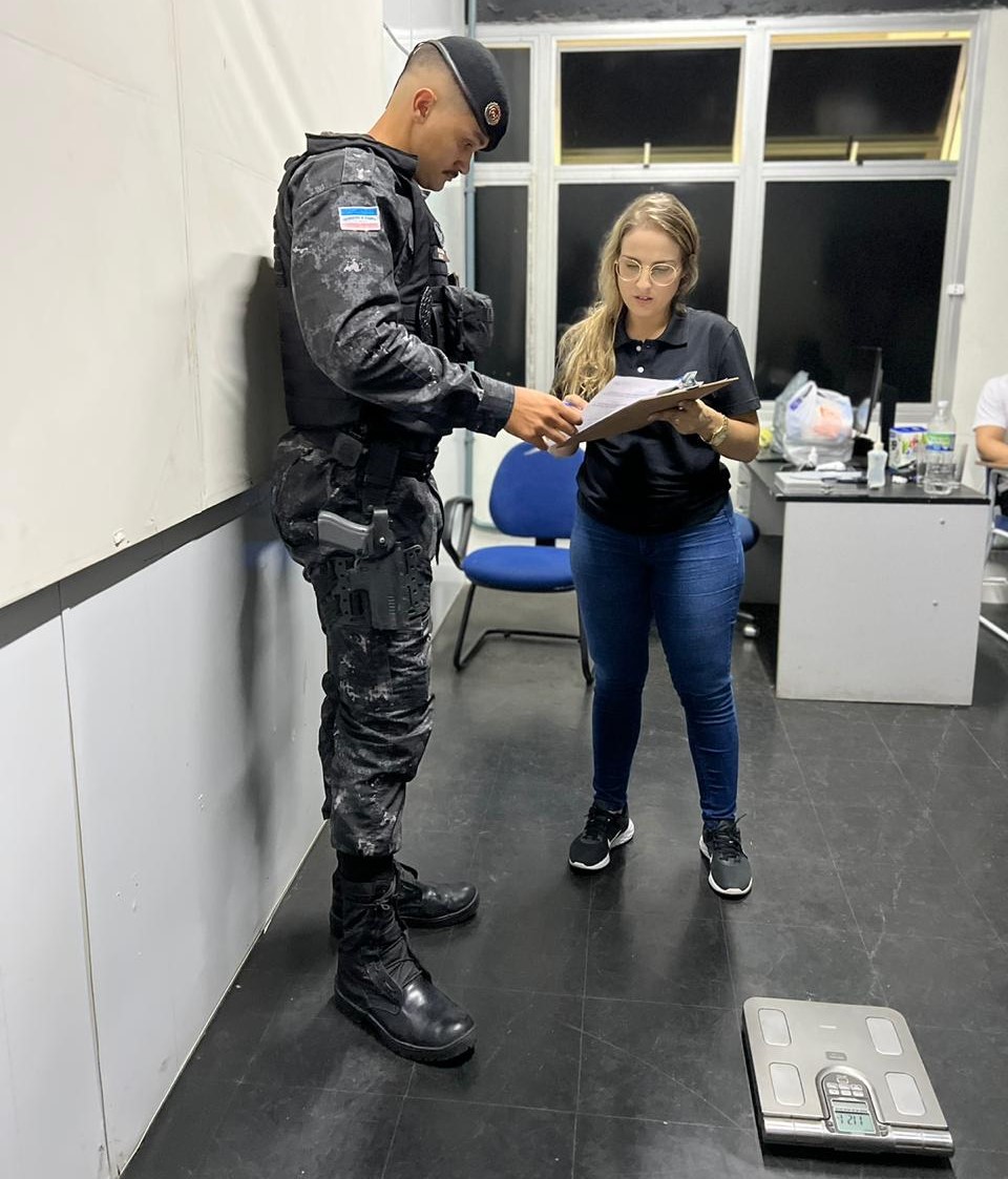 Camila Brandão realizando a avaliação em um policial, em pé e fardado