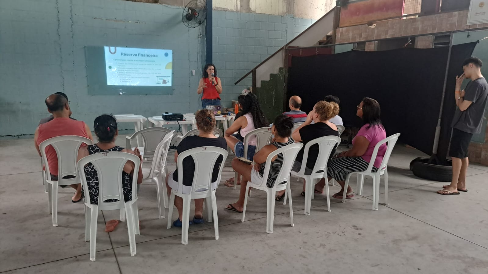 Grupo de pessoas sentadas ouvido uma palestra em um salão.