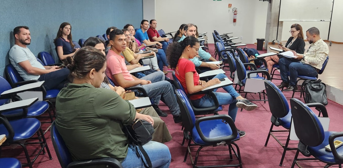 A pró-reitora Josiana Binda e o assessor Gustavo Teixeira em reunião com membros da comunidade local em uma sala de aula
