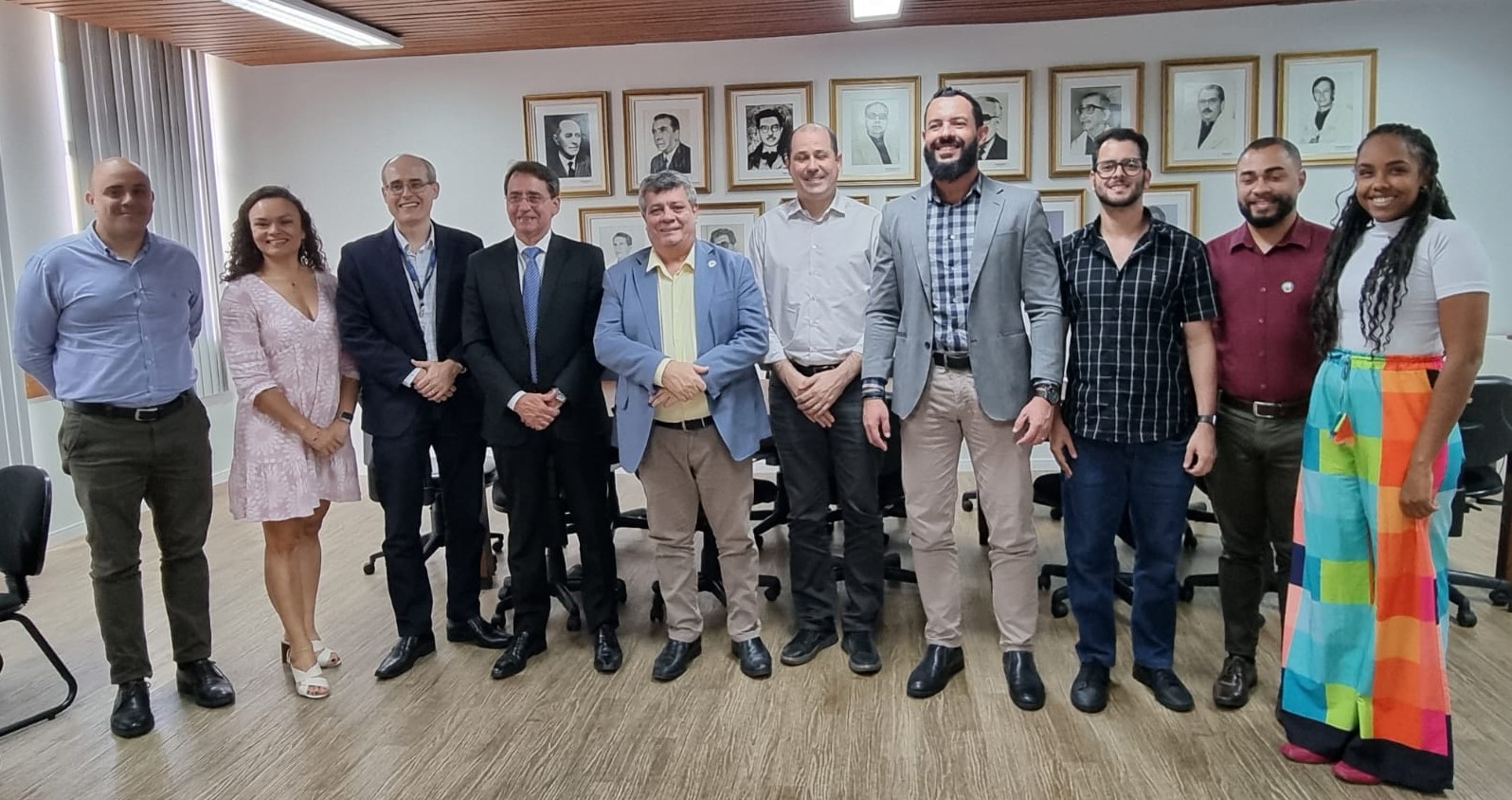 Foto de todos os presente, em pé, na sala de reuniões da reitoria. Ao fundo, a galeria de ex-reitores da Ufes