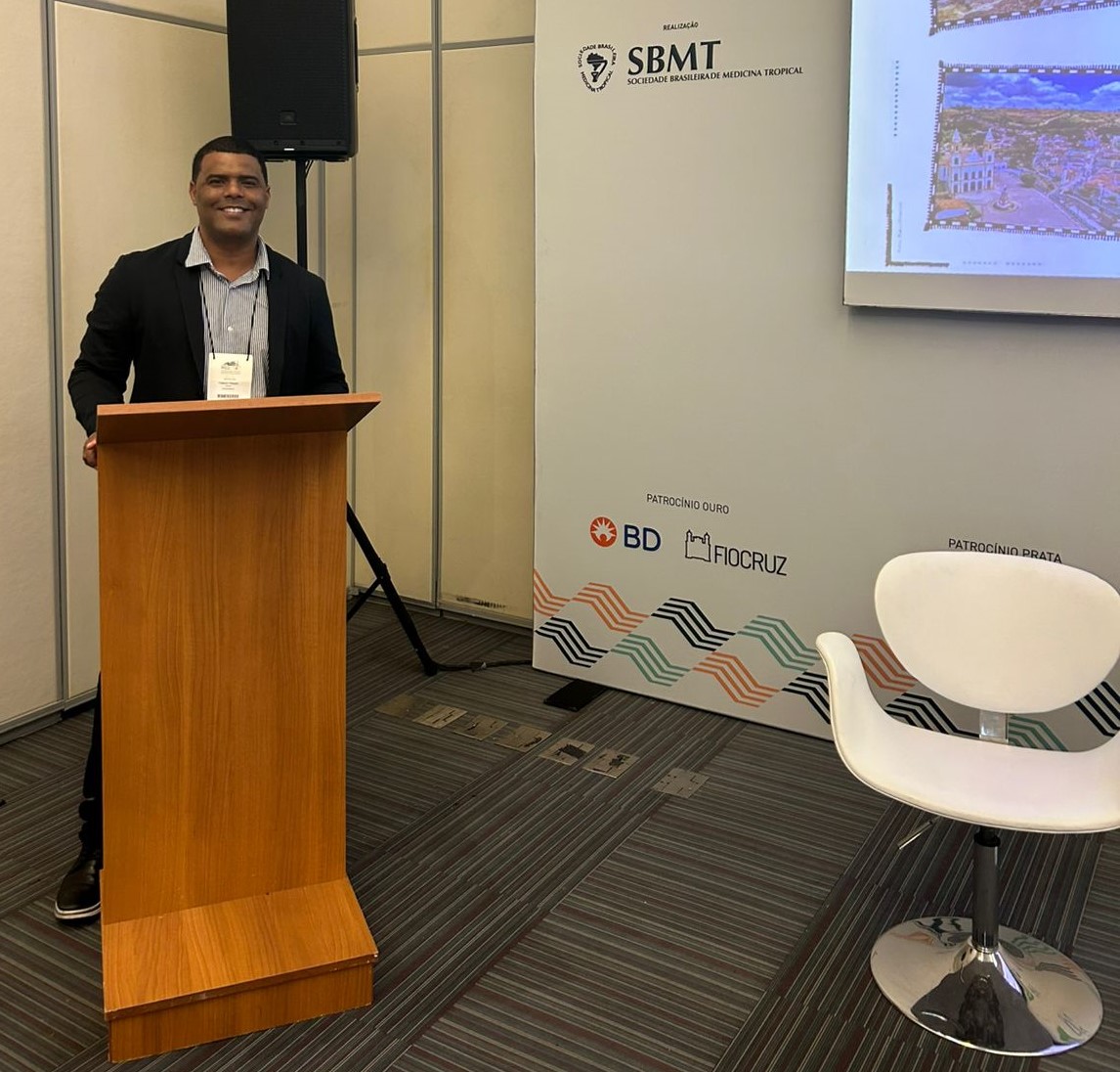 Foto do professor Thiago Prado em pé, na frente de um púlpito, em um congresso 