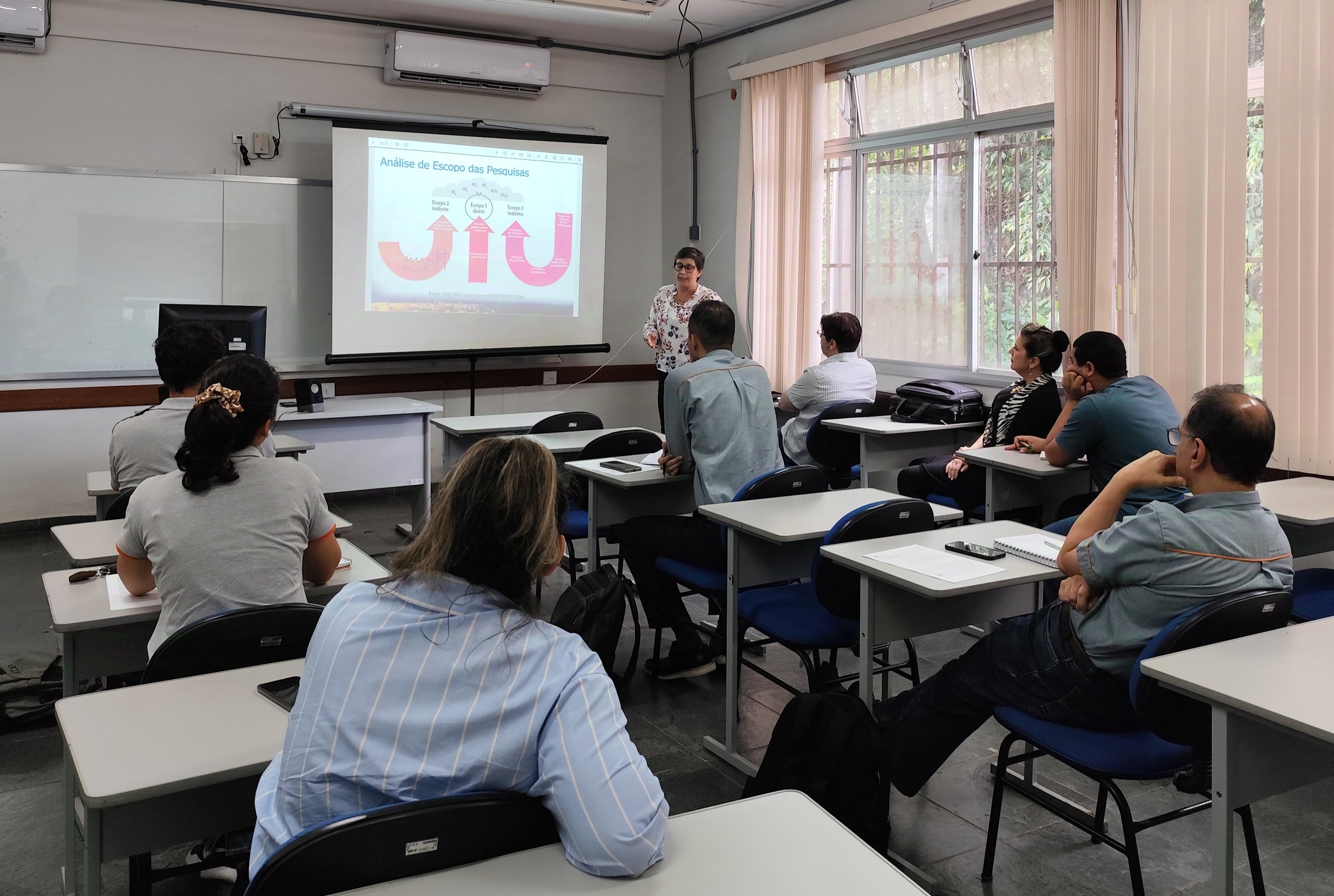 Grupo de pessoas assistindo a uma apresentação em uma sala