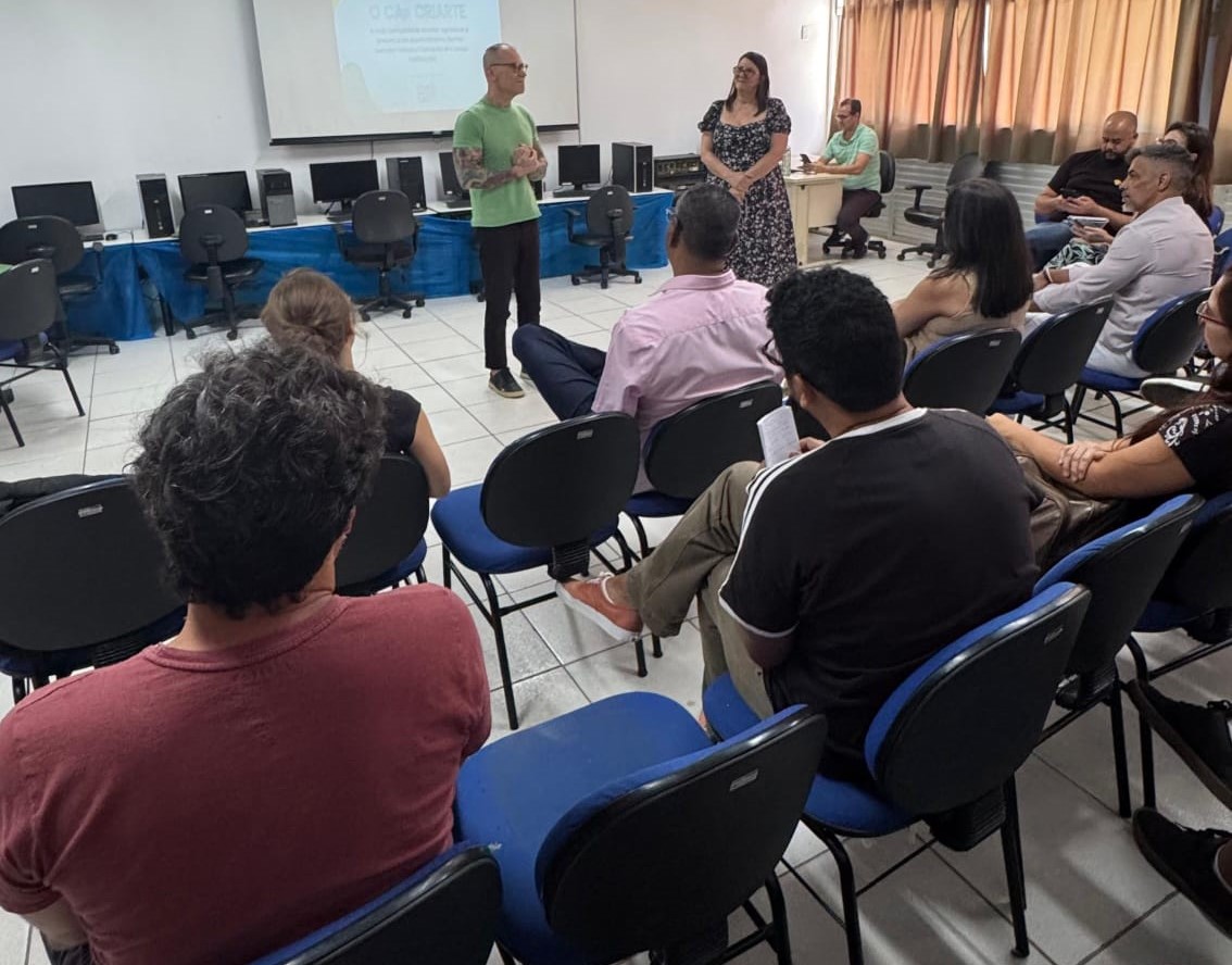 Foto do senador Fabiano Contarato e da diretora do colégio conversando em uma sala onde são ouvidos por outras pessoas que acompanharam a visita