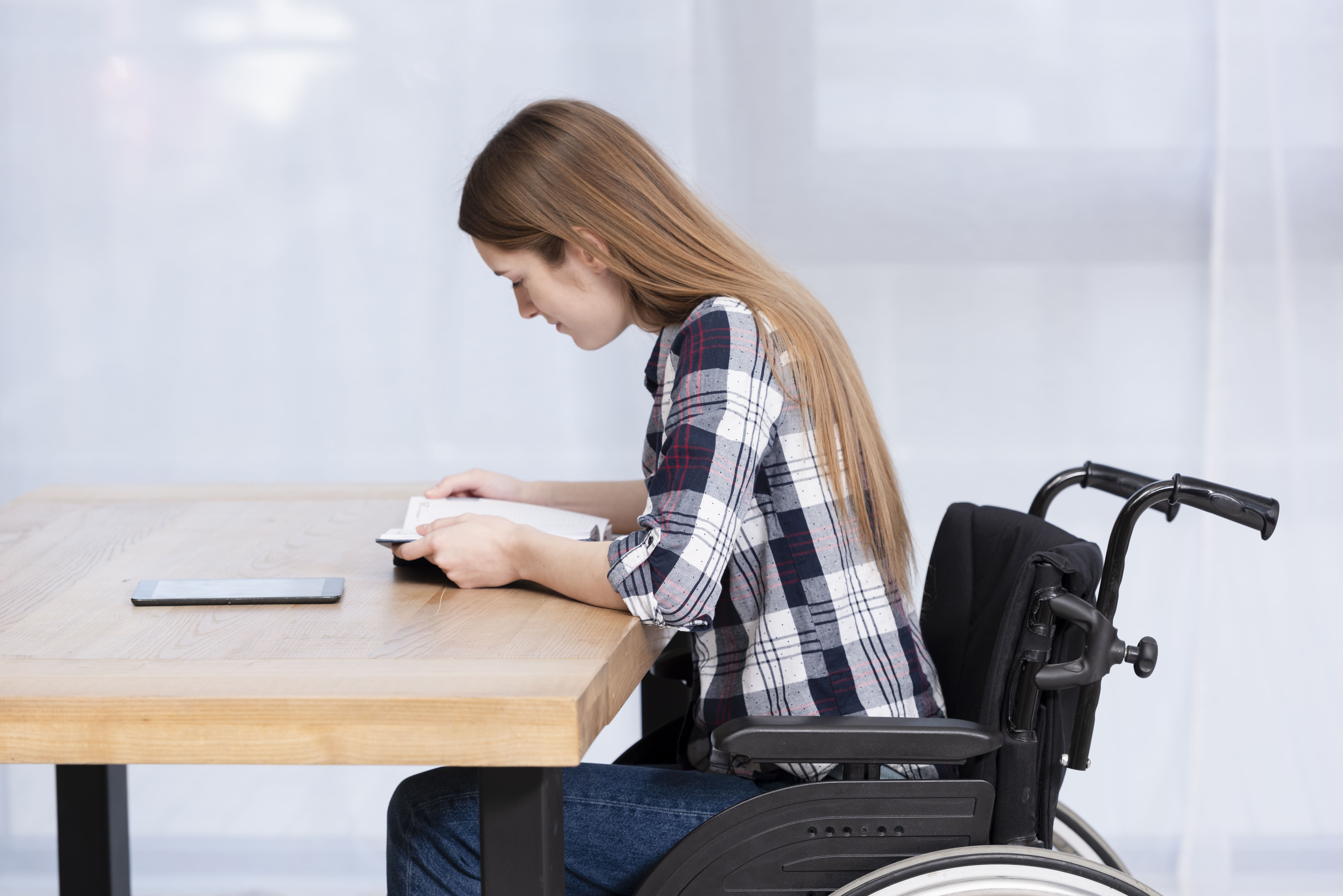 Mulher cadeirante escrevendo à mesa