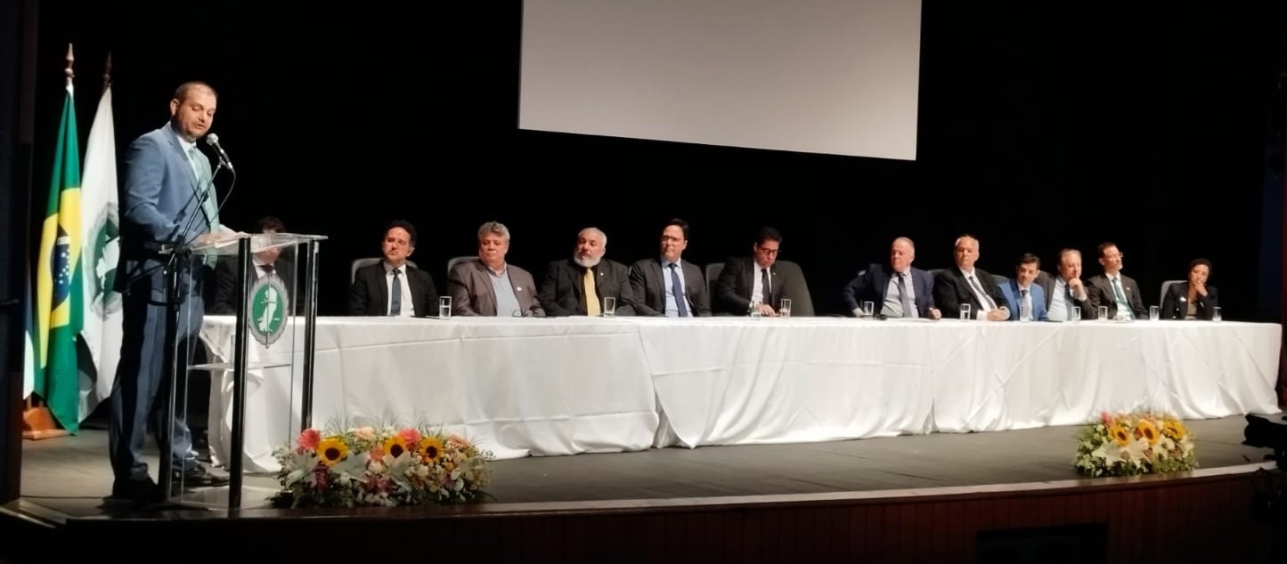 Foto da posse com o defensor público discursando e as autoridades sentadas à mesa