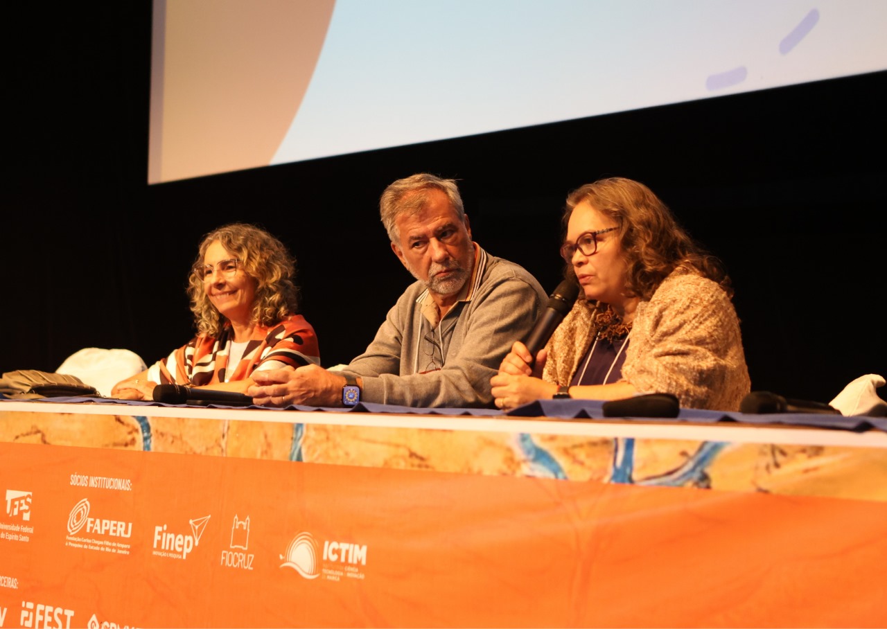 Foto da secretária-geral da SBPC, Cláudia Linhares, e dos vice-presidentes Paulo Artaxo e Francilene Garcia na mesa principal do evento, conduzindo a sessão especial