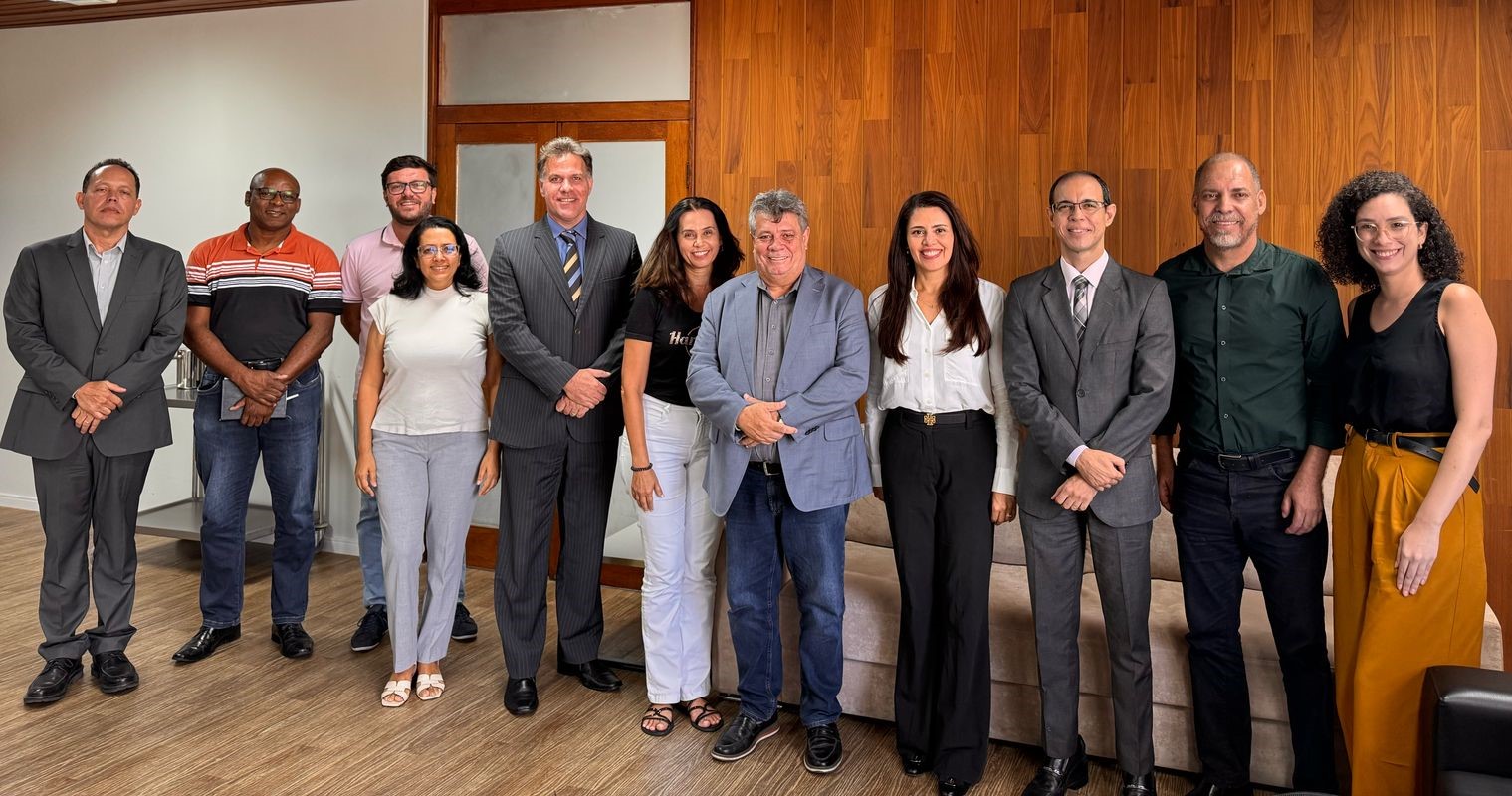 Foto de todos os presentes em pé, na sala de reuniões do Gabinete da Reitoria