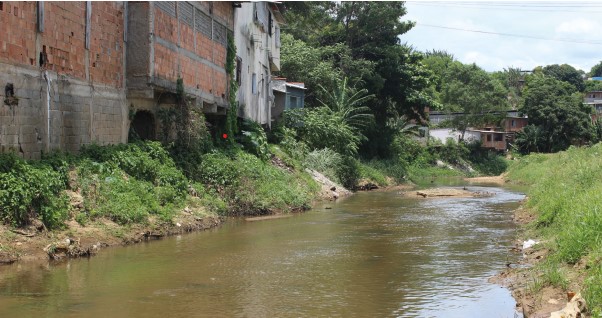 Foto do rio com casas de tijolos construídas em suas margens