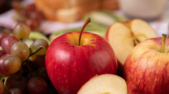 Frutas dispostas em uma mesa, como maçã e uva