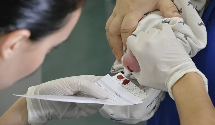 Foto de uma enfermeira coletando sangue do pé de um bebê