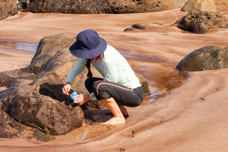 Pesquisador coletando material na areia da praia