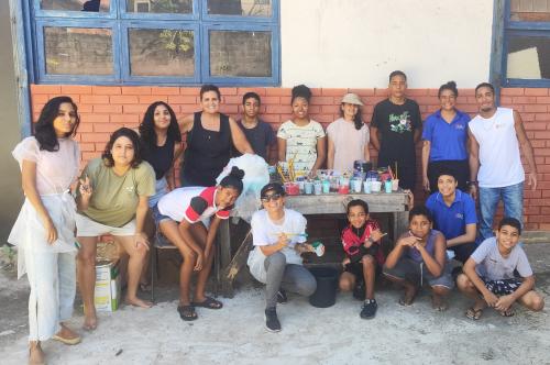 Monitores, crianças e adolescentes que participaram da pintura posando para foto.