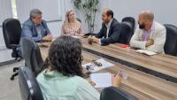 Foto da reunião, onde todos estão sentados em torno da mesa