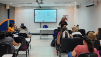 Foto da sala do seminário, com a diretora de Assistência Estudantil à frente, falando para os servidores