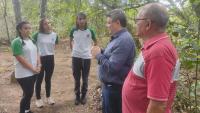 Foto do reitor da Ufes na área do manguezal falando para três estudantes. Na foto também aparece um senhor de camisa vermelha.