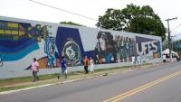 Foto do mural da Ufes com pessoas andando na calçada