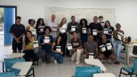Foto dos estudantes e do professor com o livro na mão