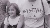 Foto de uma mulher vestindo uma camiseta em que se lê "anistia", ao lado de uma menina