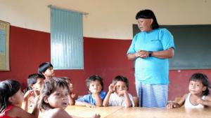 Crianças indígenas em uma sala de aula, com um professor indígena