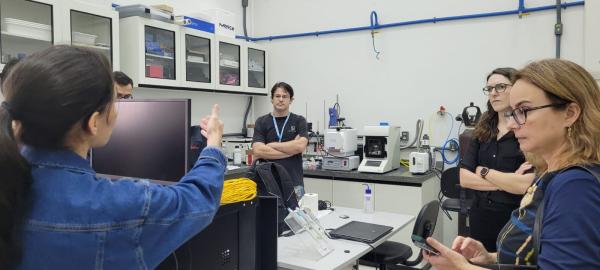 Foto das representantes do Consulado conhecendo um laboratório da Ufes