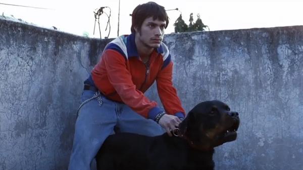 Cena de Amores Brutos, na qual aparece um homem segurando um cachorro pela coleira