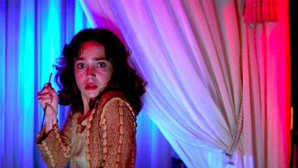 Cena de Suspiria onde aparece uma mulher olhando para a câmera com expressão de surpresa