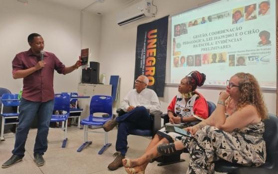 Foto do pesquisador apresentando o estudo para três pessoas