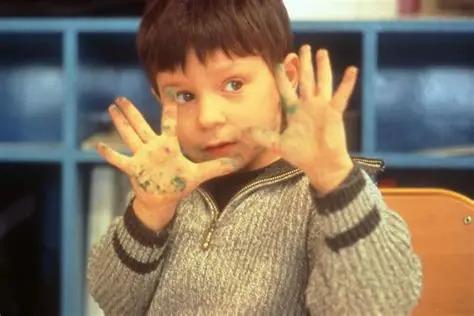 Cena do filme Ser e Ter, na qual aparece um menino mostrando as mãos