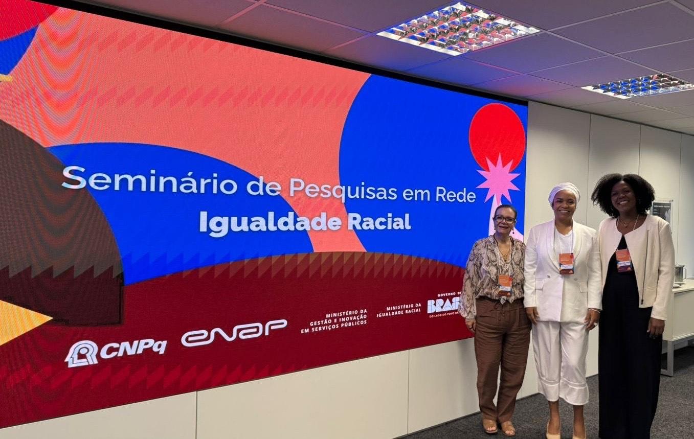 Foto das professores em frente ao painel do evento