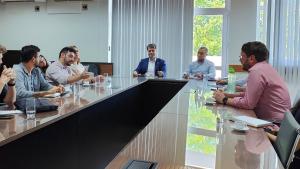 Foto dos participantes sentados à mesa de reunião 