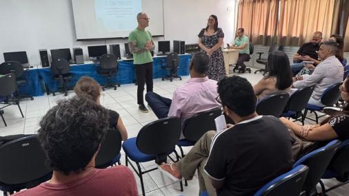 Foto do senador Fabiano Contarato e da diretora do colégio conversando em uma sala onde são ouvidos por outras pessoas que acompanharam a visita