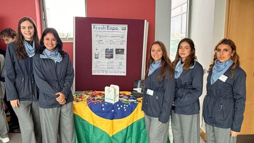 Foto da equipe envolta de uma mesa coberta com a bandeira do Brasil e o prêmio sobre ela